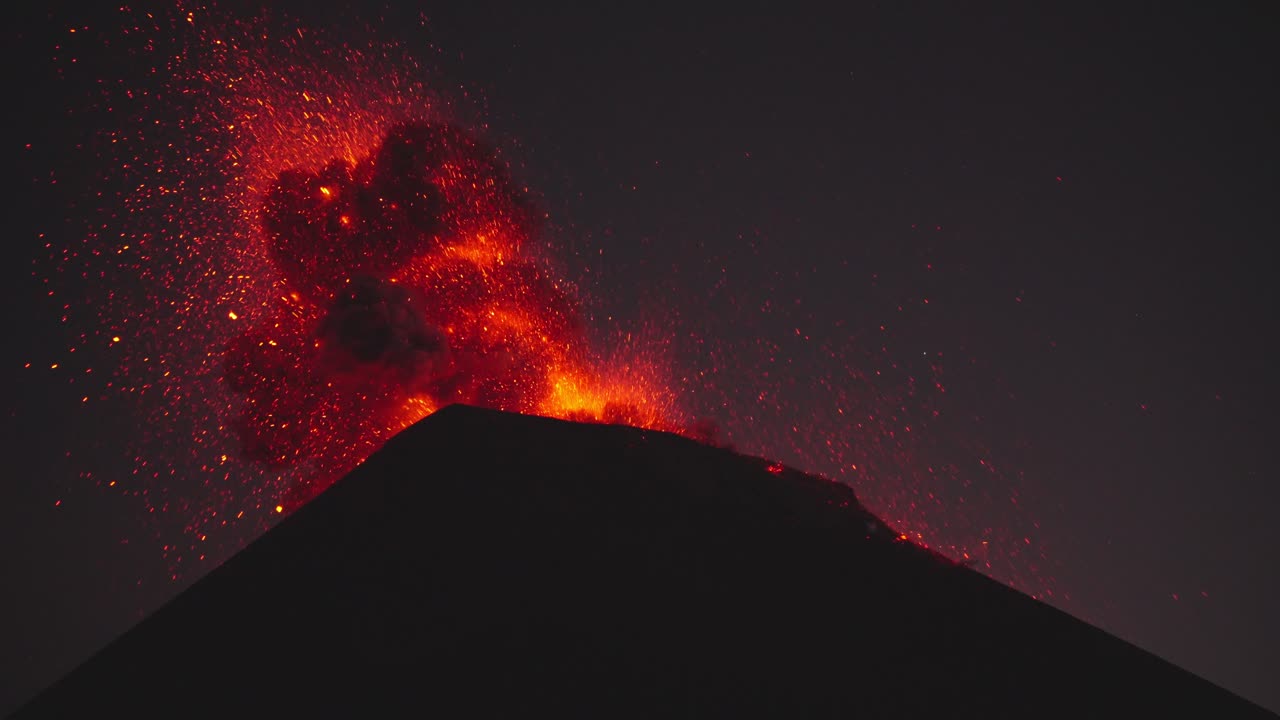 Dramatic close-up of Fuego Volcano's erupting crater at night, spewing large amounts of molten lava into sky