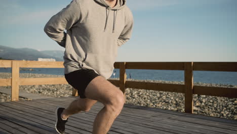 man stretching on a wooden pier at the beach