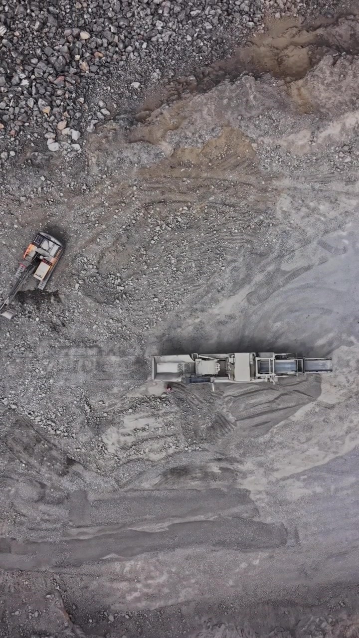Heavy machinery works on a construction site in a rocky area during the day