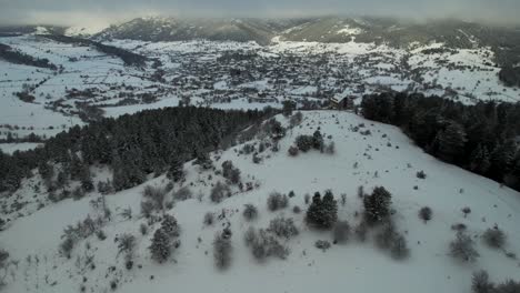 Beautiful-countryside-in-winter-with-village-houses-and-forest-covered-in-white-snow-in-Voskopoja,-Albania