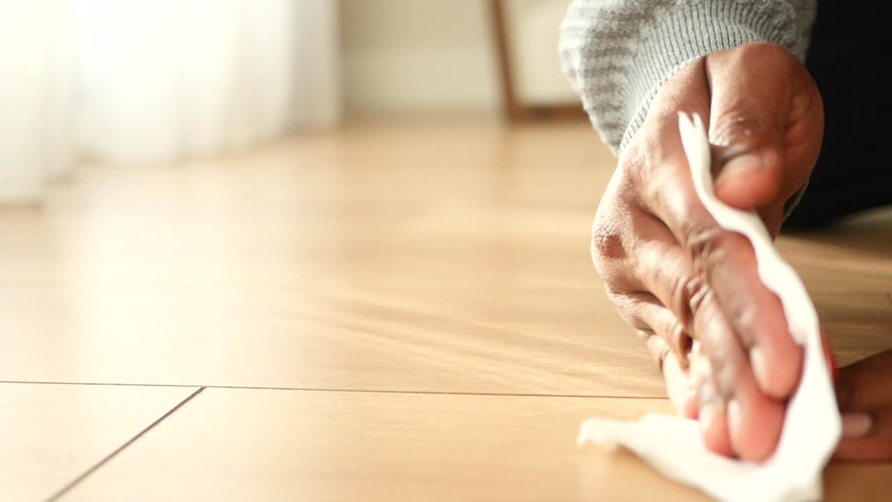 una persona limpiando el suelo con una toalla