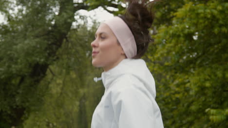 primer plano de una mujer con una cinta para la cabeza haciendo ejercicio manteniéndose en forma corriendo en el campo o en el parque 4