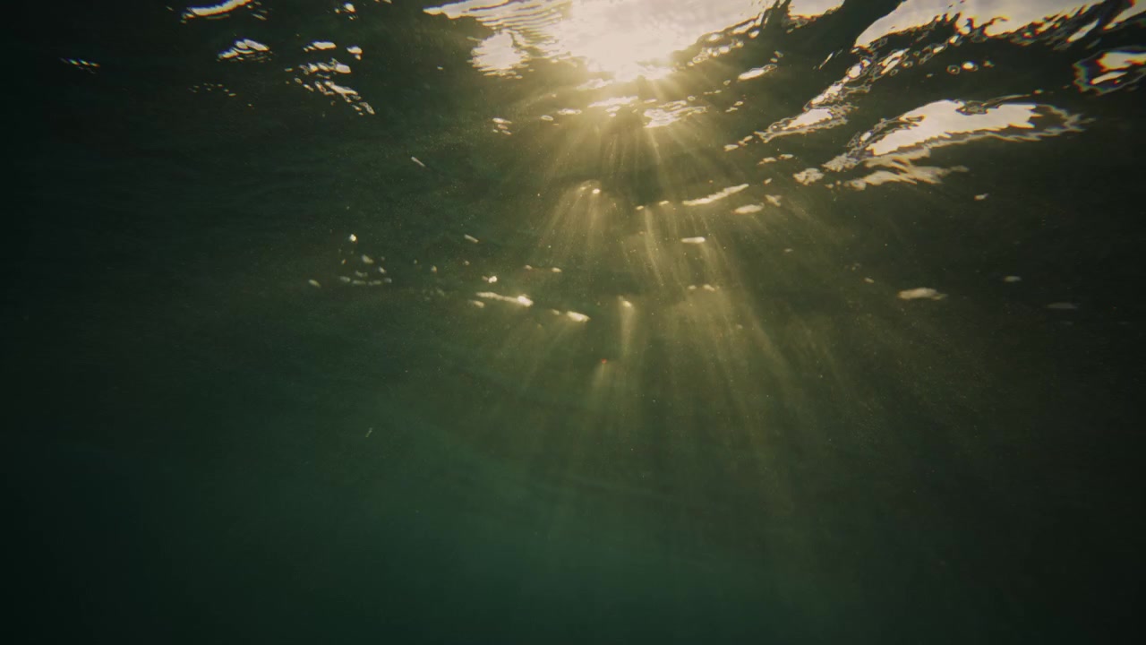 Bokeh light bubbles reflect on ocean water surface at sunrise