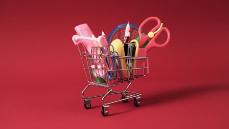 Close-up-of-shopping-trolley-with-school-items-and-copy-space-on-red-background