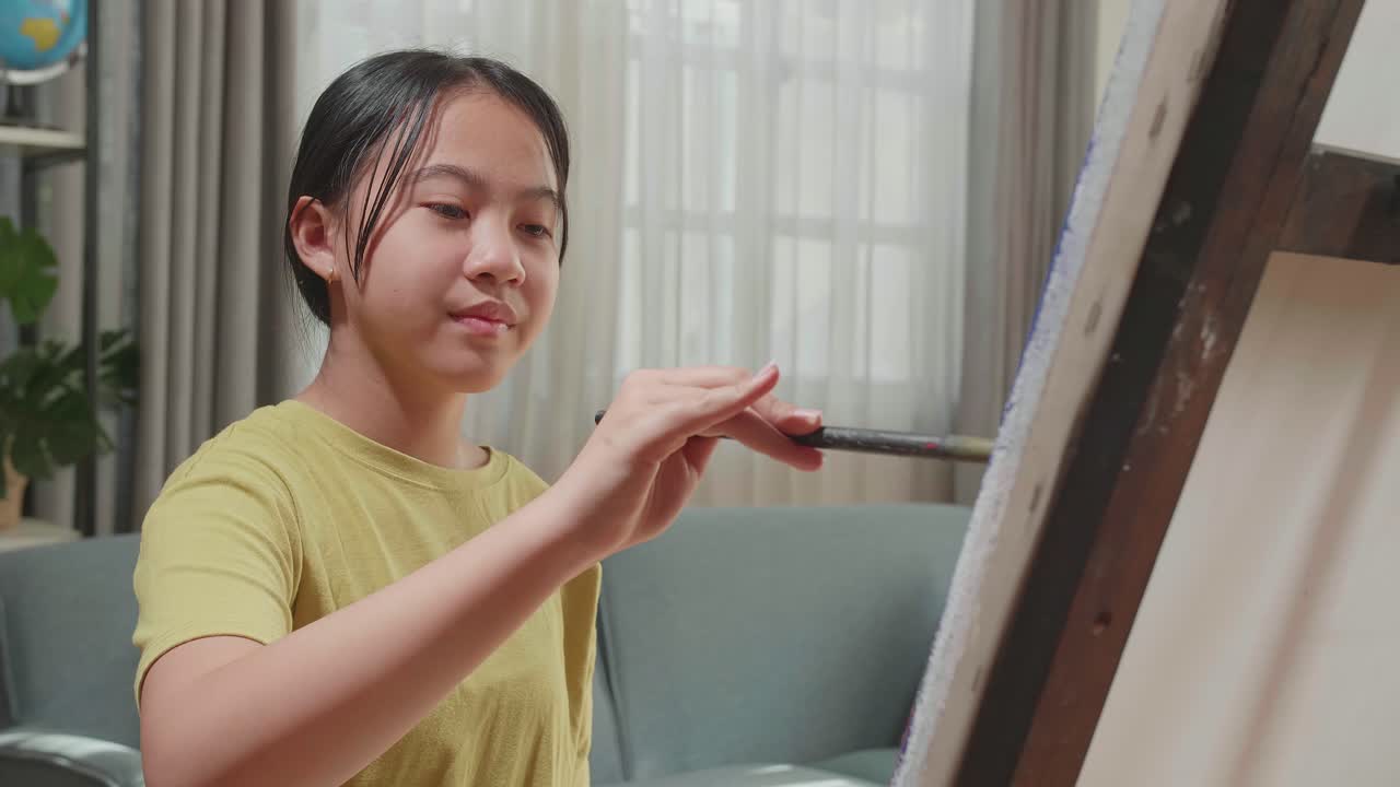 Asian Artist Girl Holding Paintbrush Mixed Colour And Painting On The Canvas