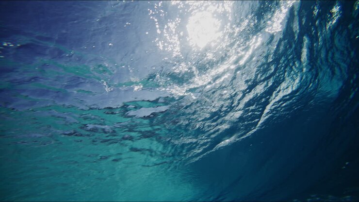 Vista subacquea di onde che si formano in una piscina a onde, ripresa al rallentatore mostra riflessi e schemi di onde dinamici, silhouette sognante di un surfista.