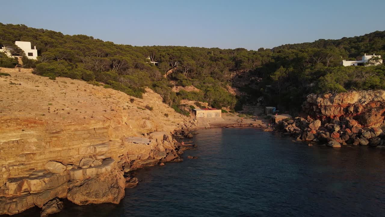 Luftfoto der omslutter kystlinjen under solnedgang, folk på stranden, optaget på Ibiza, Spanien.