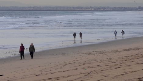 People walking down beach at high tide
