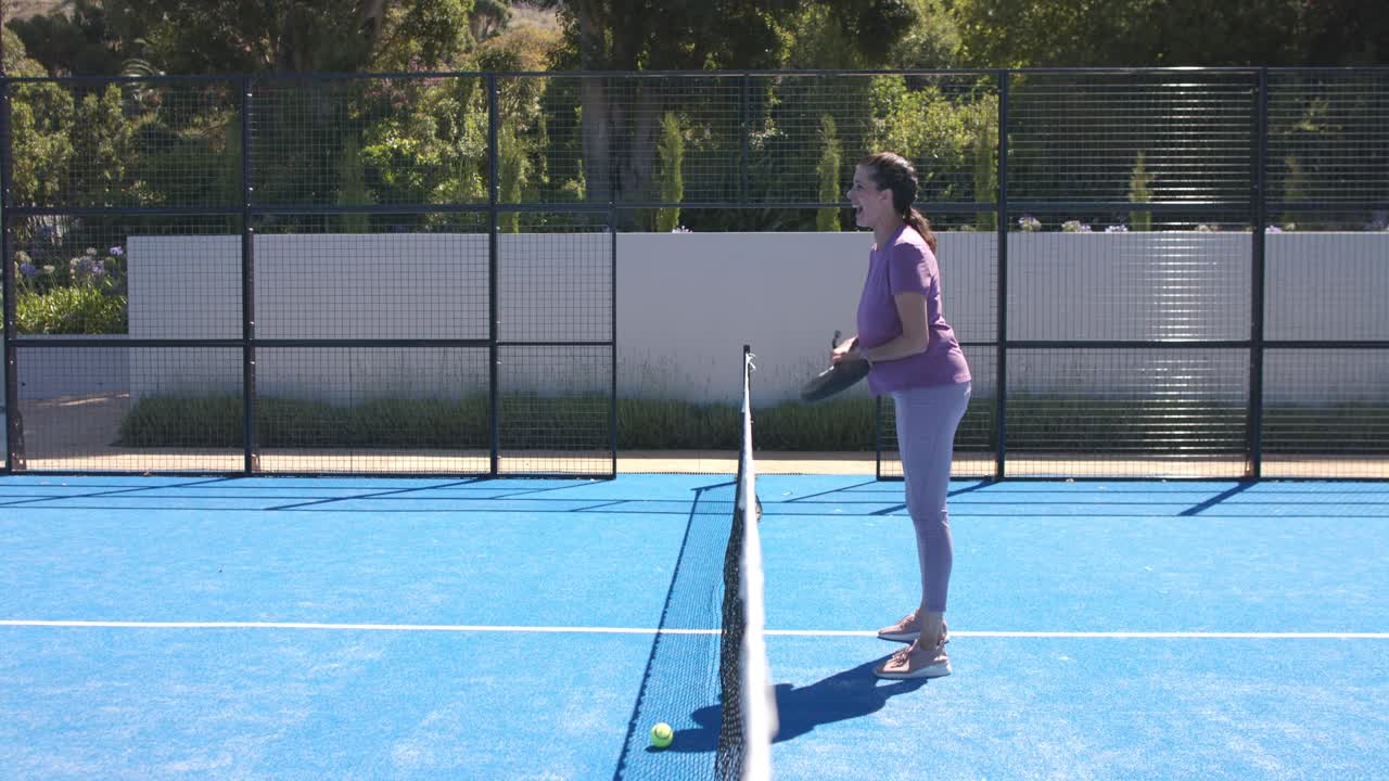 Mulheres diversas em quadra azul, a primeira lançando a bola e a segunda, de viseira, batendo com as raquetes, com espaço para texto.