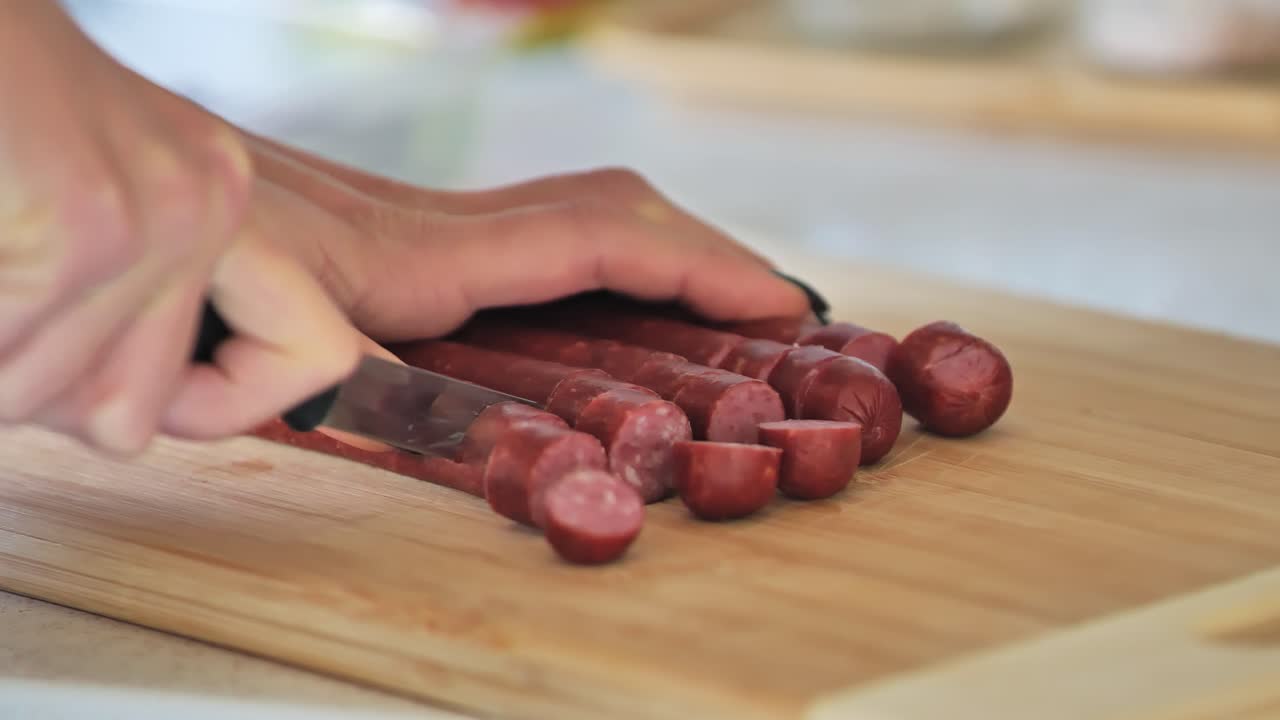 Cooking preparation with sausages being cut into pieces, filmed in a kitchen