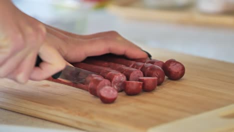 cooking preparation with sausages being cut into pieces, filmed in a kitchen