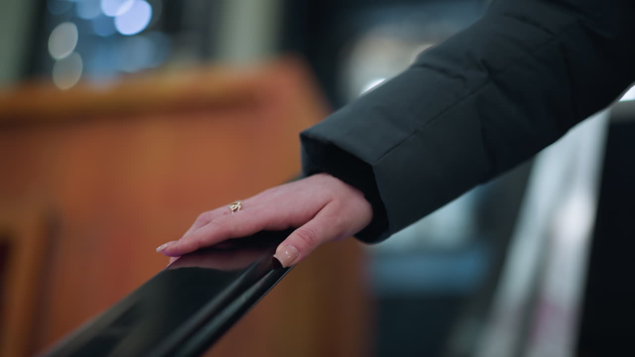 primer plano de clavos bien pulidos colocados suavemente en el riel de una escalera mecánica móvil, enmarcado con vidrio, el fondo borroso presenta un ambiente urbano suave