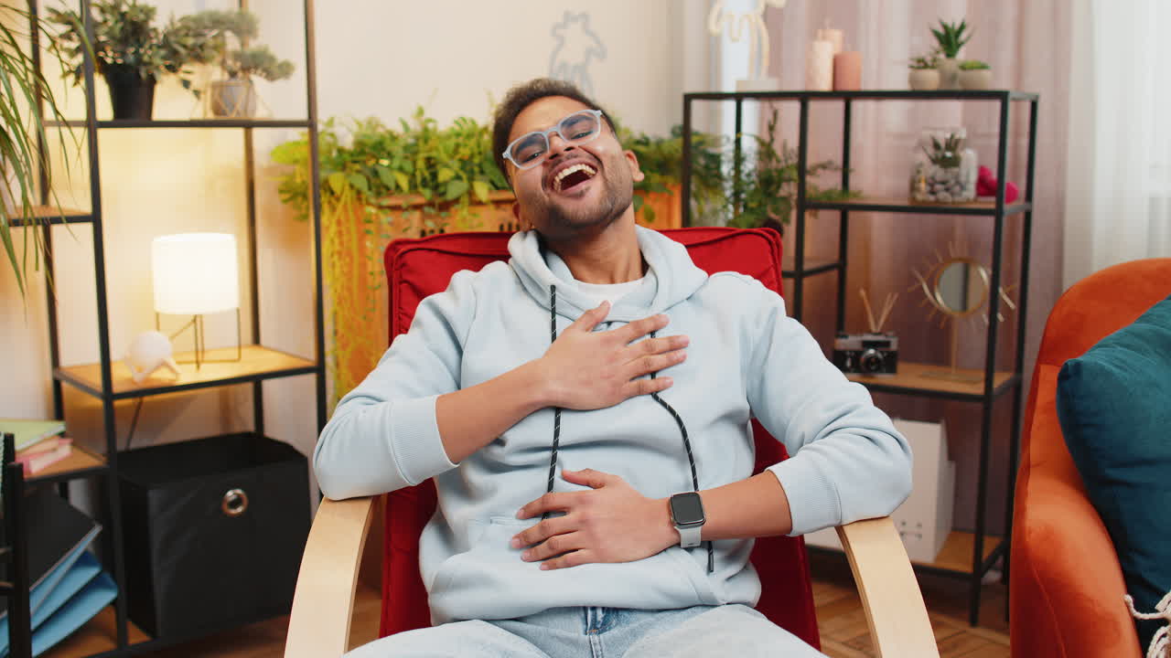 Indian man laughing out loud after hearing ridiculous anecdote funny joke feeling carefree amused