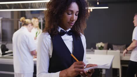 African-American-female-restaurant-manager-in-the-kitchen,-looking-at-camera,smiling