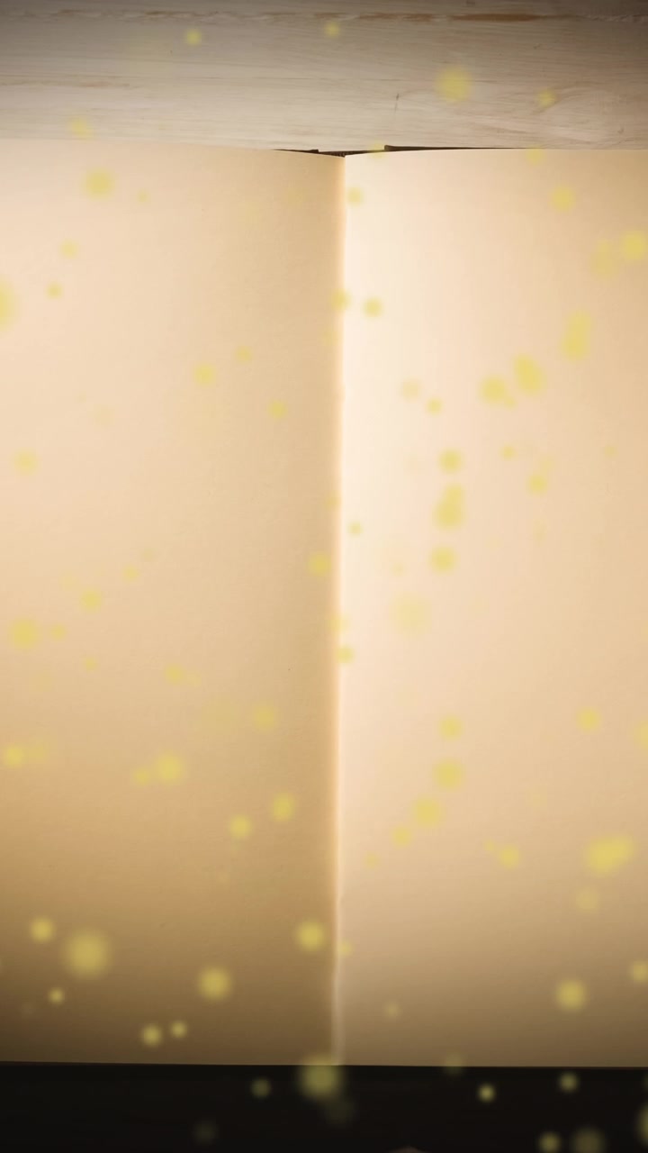Animation of yellow glowing spots over open book with copy space