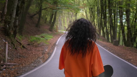 woman hiking with skateboard in forest