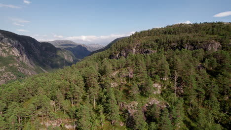 Aerial-shot,-panning-across-a-tree-covered-mountain-top-in-Norway