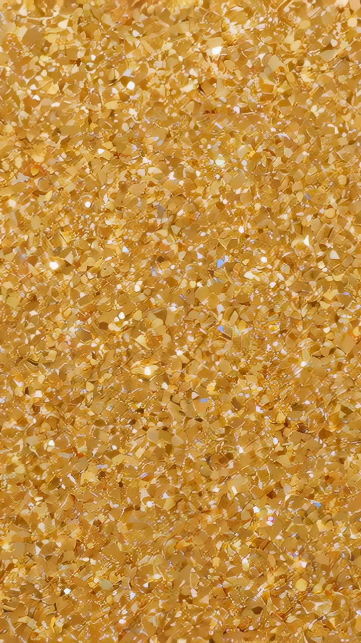 Vertical video: Shimmering gold sequin flakes shifting with studio light moving in macro, foil