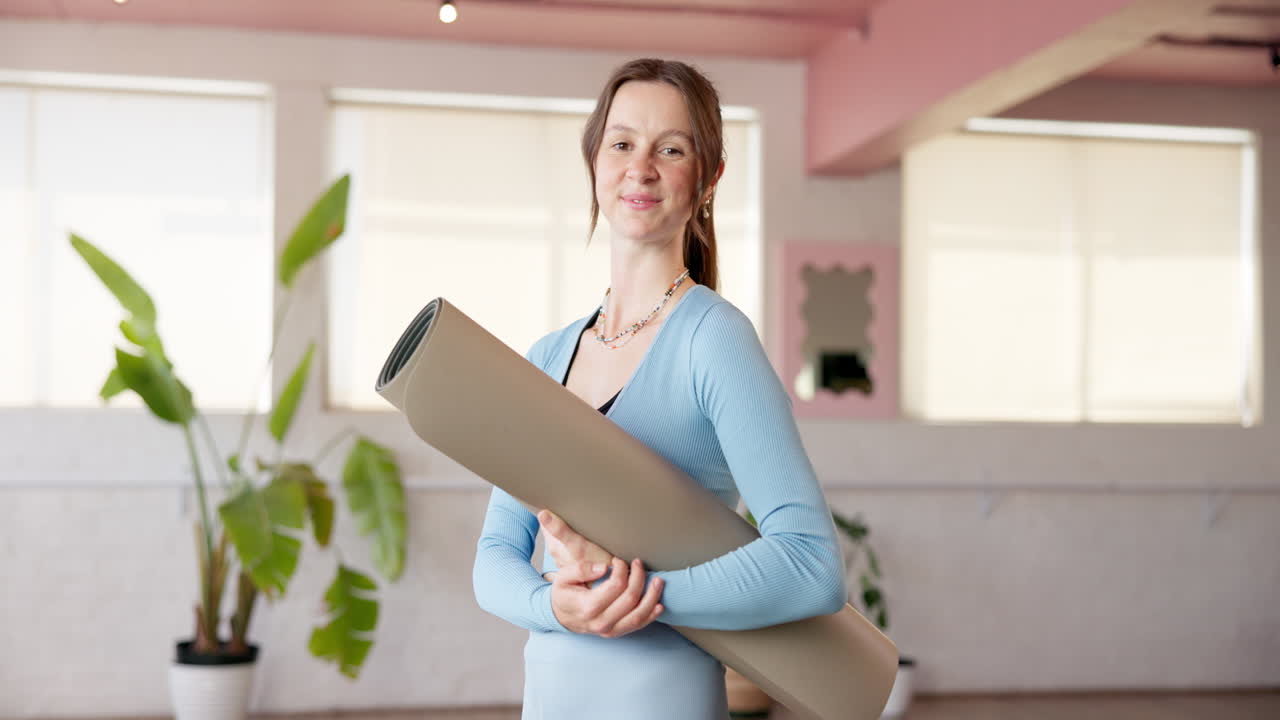 Una donna che tiene in mano un tappetino da yoga in uno studio