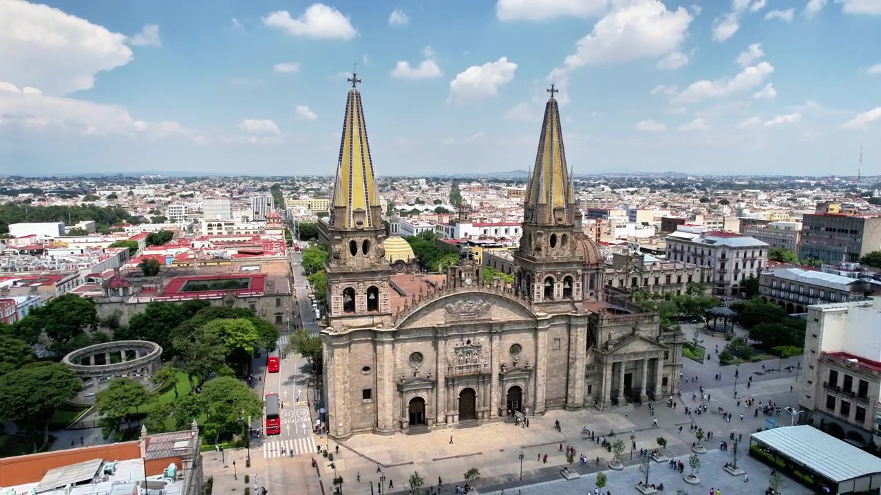 Órbita cinematográfica de drone em torno da Catedral de Guadalajara, exibindo suas icónicas torres gêmeas e o centro histórico da cidade circundante.