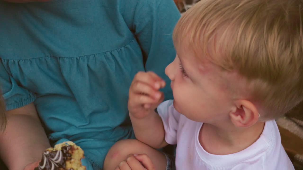 엄마와 아이의 얼굴이 사랑스럽게 가까워지고 둘 다 웃으며, 아이가 코를 만질 때 엄마는 케이크를 들고 있습니다.