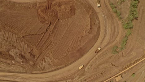 Wide-angle-top-down-aerial-view-of-dump-trucks-hauling-nickel-ore-across-the-mining-sites-of-Taganito-in-Claver,-Philippines