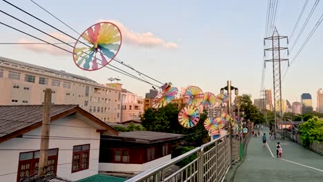 pinwheels rotate above urban walkway at sunset.