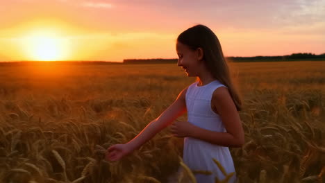 young girl walking through a golden wheat field at sunset