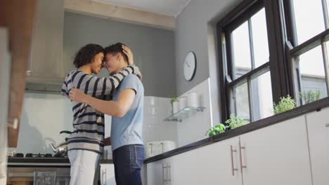 happy diverse male couple smiling and dancing together in kitchen