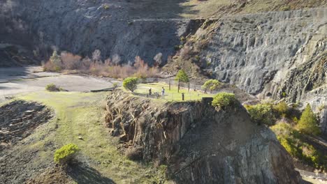 360-panning-drone-footage-of-rocky-forested-valley-on-a-bright-sunny-day-in-Auburn,-California,-USA,-showing-3-hikers-on-a-parkland-terrace