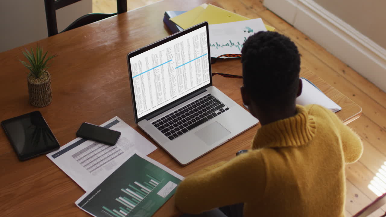 African american man sitting at desk coding data on laptop