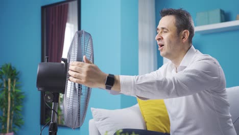 Overwhelmed-by-the-heat,-the-man-is-holding-the-fan-to-himself.