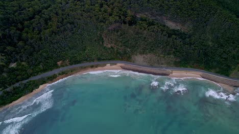 Top-down-drone-view-of-Australia's-Great-Ocean-Road-highway-with-aqua-ocean-water-and-remote-forest-in-Victoria