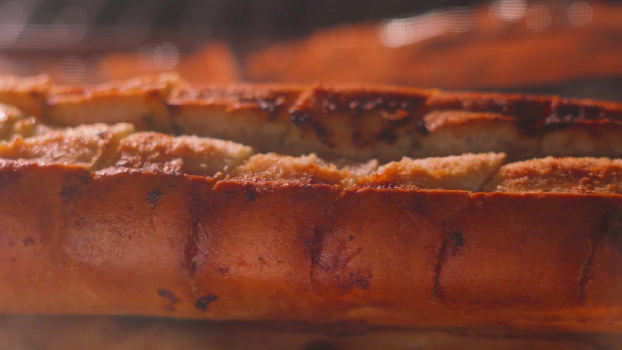 Dolly Shot Across Hot Cooking Garlic Bread Baguette in Oven.