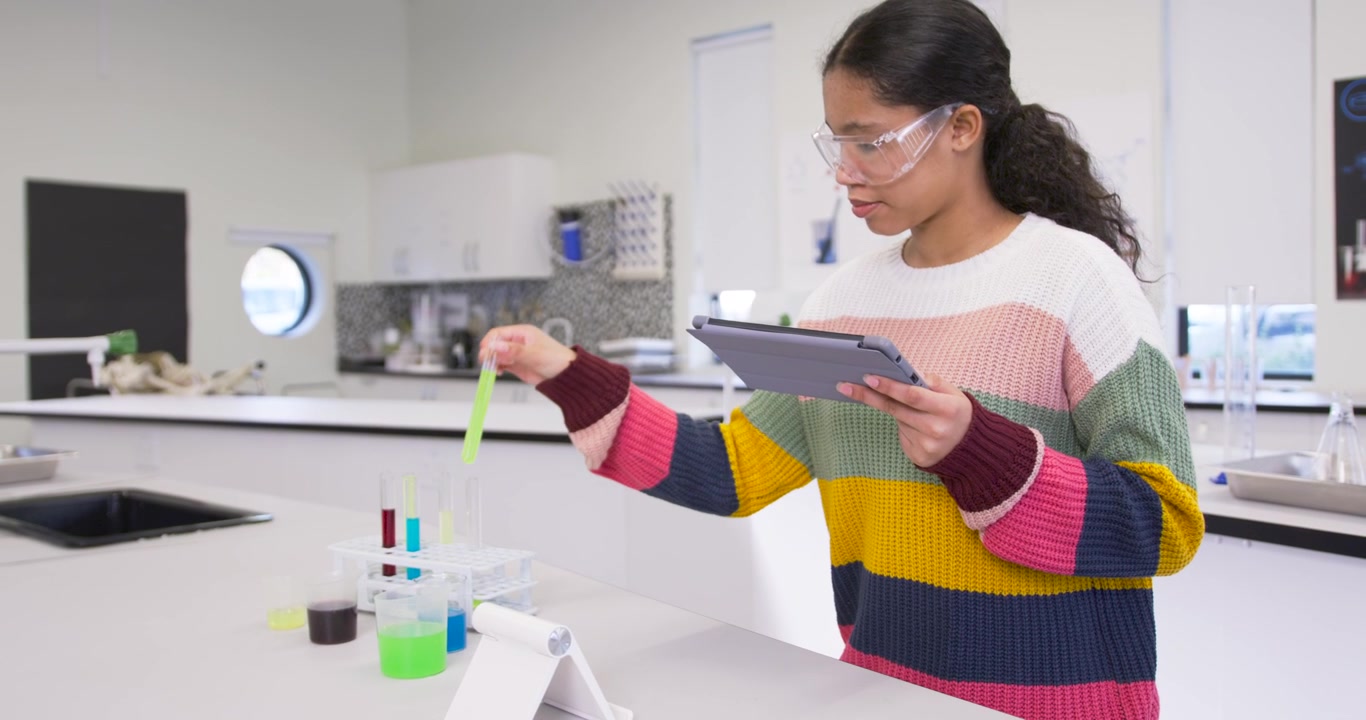 Child consulting tablet, following instructions and inspecting green tube on lab bench, copy space