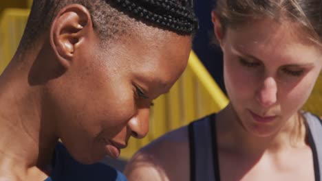 mujeres multiétnicas usando un teléfono en la playa y el fondo del cielo azul