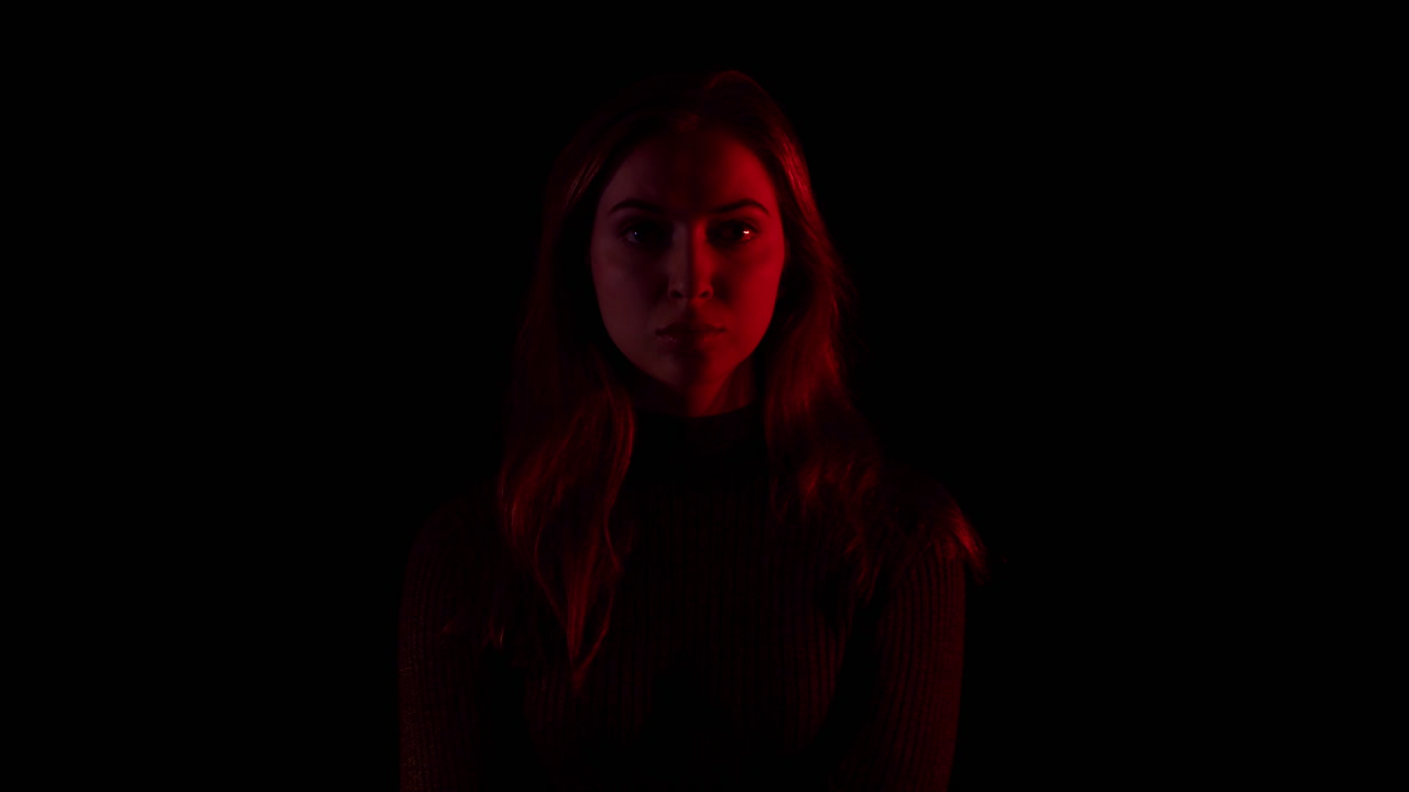 A flashing light illuminates a sad depressed woman. She suffers from loneliness and isolation. She's got covid symptoms, she's broken