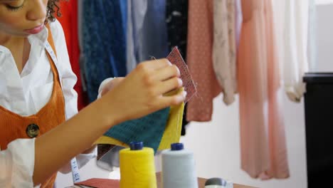 front view of african american female fashion designer looking at cloth samples in workshop 4k