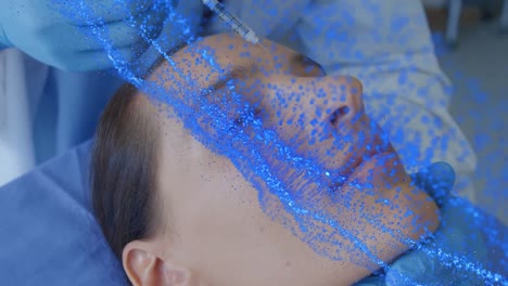 animation of network of blue particles over surgeon treating caucasian female patient