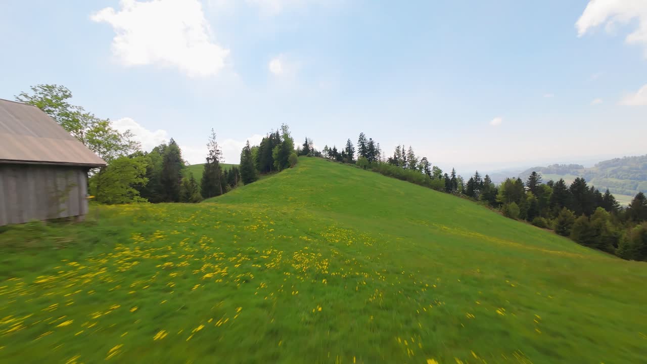 Fpv drone flight over green mountains of Switzerland with walking couple during hiking trip. Wide shot. Forest landscape on top of hills during cloudy day in summer.