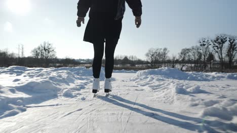 professional female skater in white figure skates is skating on frozen lake. woman feet are skating on ice on river in winter. ice-skating winter activities