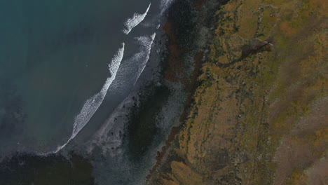 aerial view of waves softly crashing to the shore in iceland