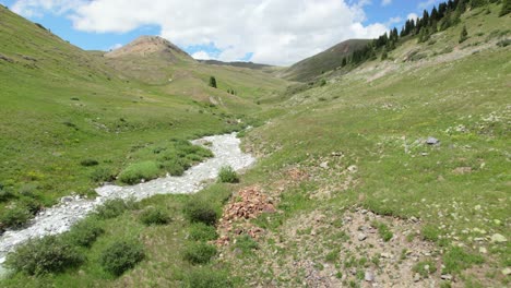 a forward drone shot flying slowly over a crystal clear blue river of snowmelt mineral water in the san juan mountains in the summertime