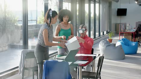 caucasian businessman wearing vr headset while colleagues watching him at office