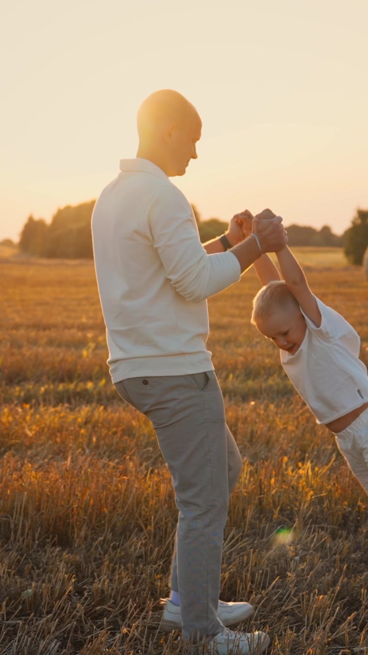 Padre che gioca e fa volteggiare il suo giovane figlio in un campo di grano dorato