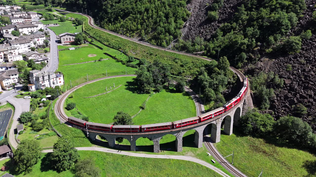Train on scenic curved viaduct, lush greenery, daytime, aerial view
