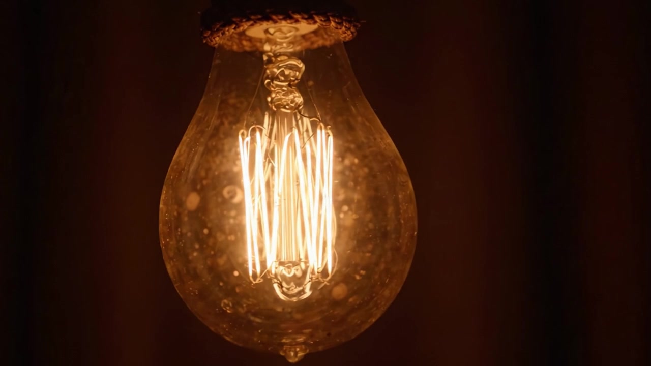 Eleganza Illuminante: Un Primo Piano di una Lampadina Vintage che Brilla Caldamente in un Ambiente Fioco, Mettendo in Mostra il Design Intricato del Filamento e un'Atmosfera Accattivante