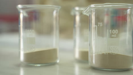 Science-beakers-partially-filled-with-white-powder-chemicals-ready-for-research