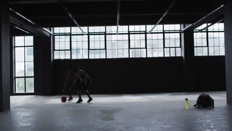 hombre y mujer afroamericanos de pie en un edificio vacío jugando al baloncesto