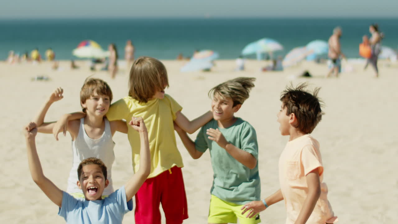 передний вид подростков-футболистов, прыгающих от радости на пляже.